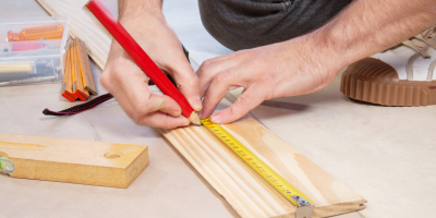 Cropped hand of a carpenter taking measurement of a wooden plank